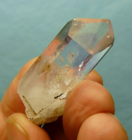 A gemmy quartz crystal with faint amethyst colouring, a few small negative crystal inclusions, and a few pieces of quartz near its bottom end.