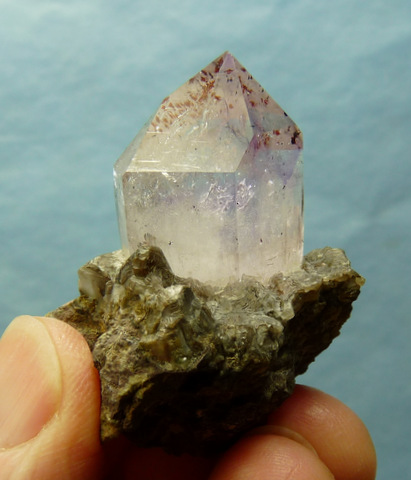 Light amethyst quartz crystal with hematite specks, on matrix