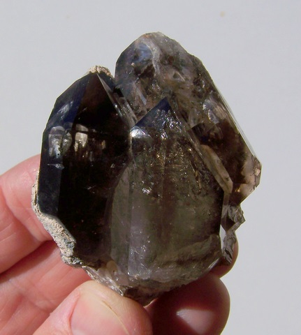 Group of gemmy smoky quartz crystals with crystal inclusions.