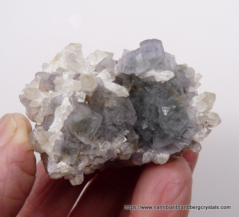 Dark (mostly purple) fluorite crystals with feldspar, on matrix